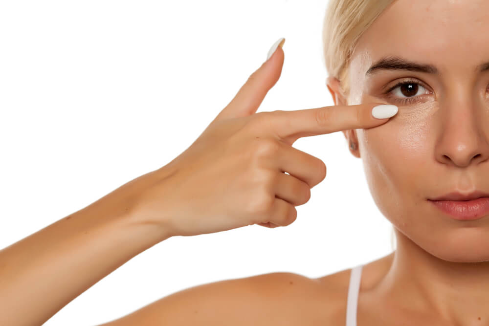Mujer aplicándose poco corrector de ojeras para evitar errores de maquillaje que envejecen