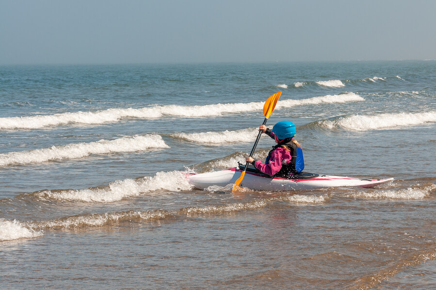 Una mujer se dirige hacia el mar para tomar una ola.